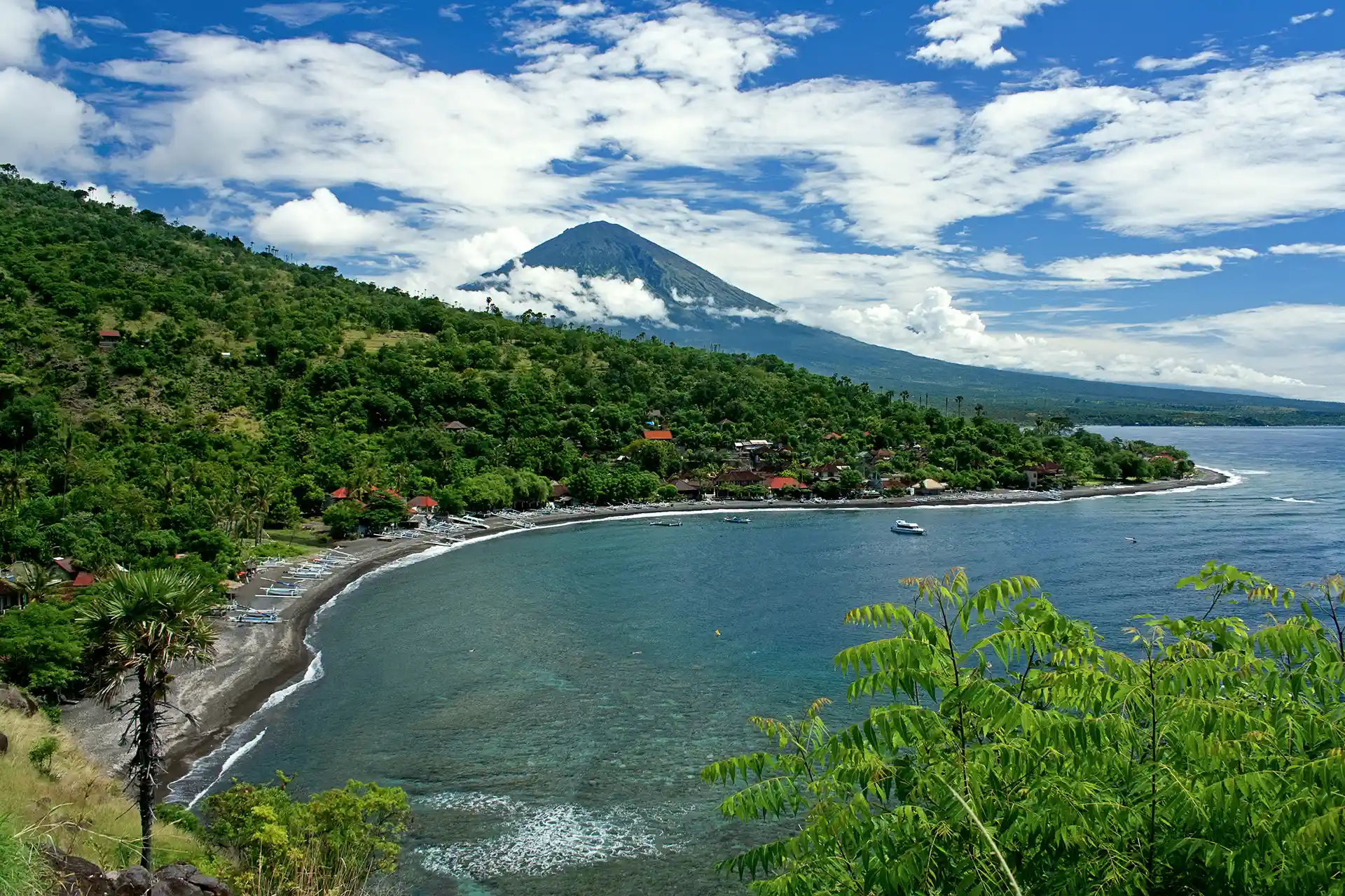 High-angle view of a crescent-shaped dark sand beach bay