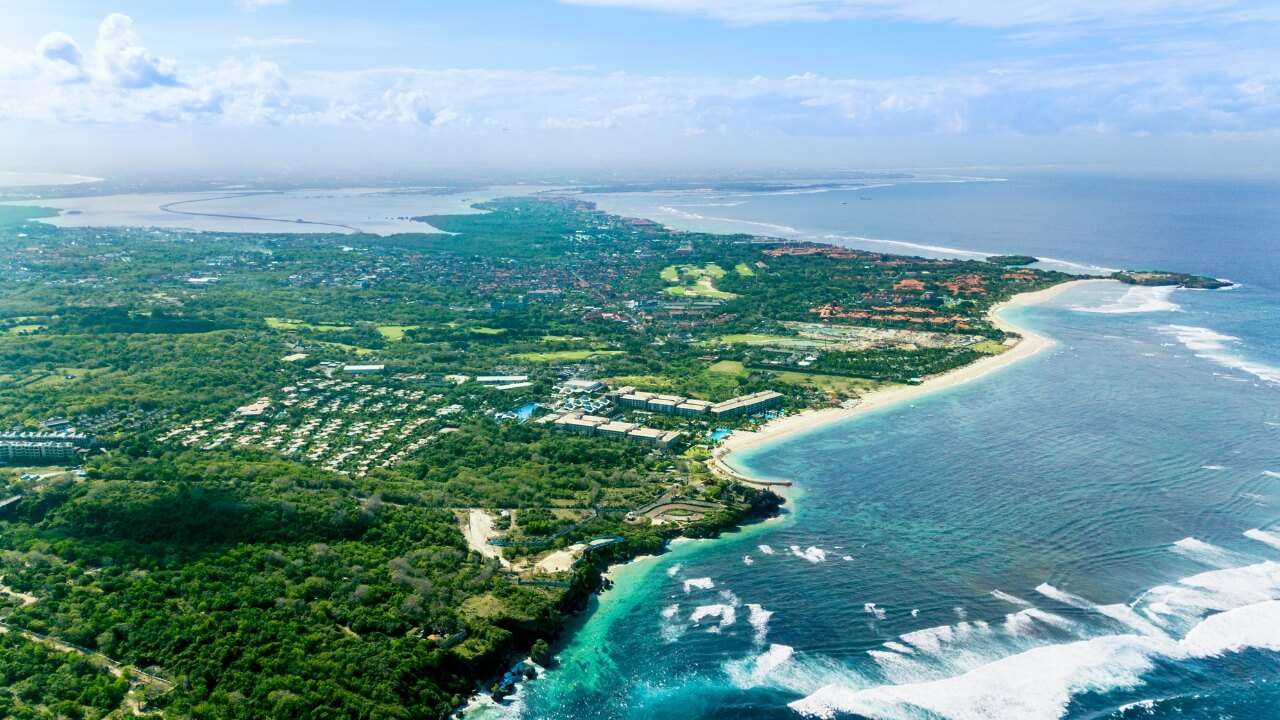 Aerial bird's-eye view of a lush tropical resort coastline with white sand beaches and turquoise ocean water.