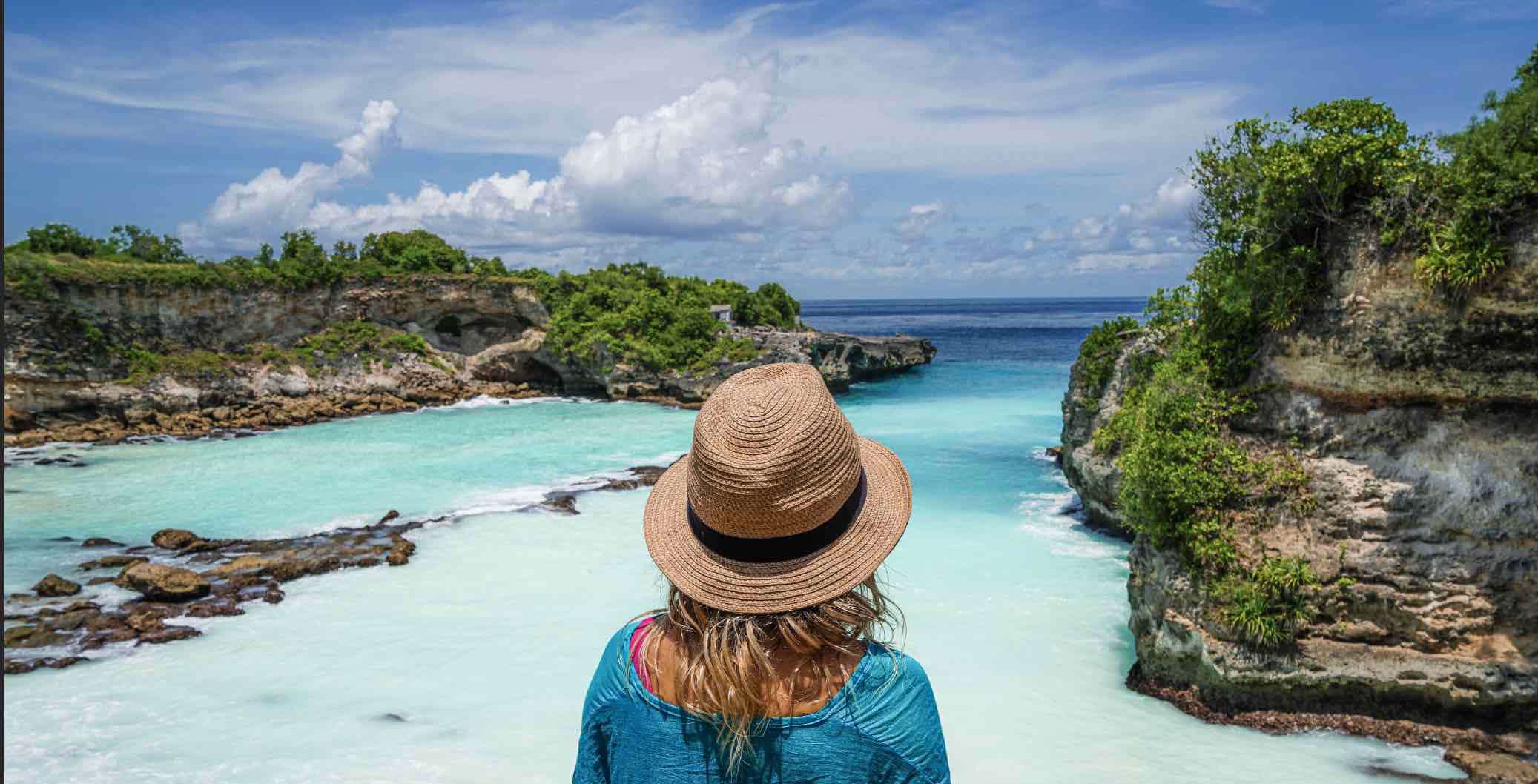 Woman looking out over a vibrant turquoise ocean cove